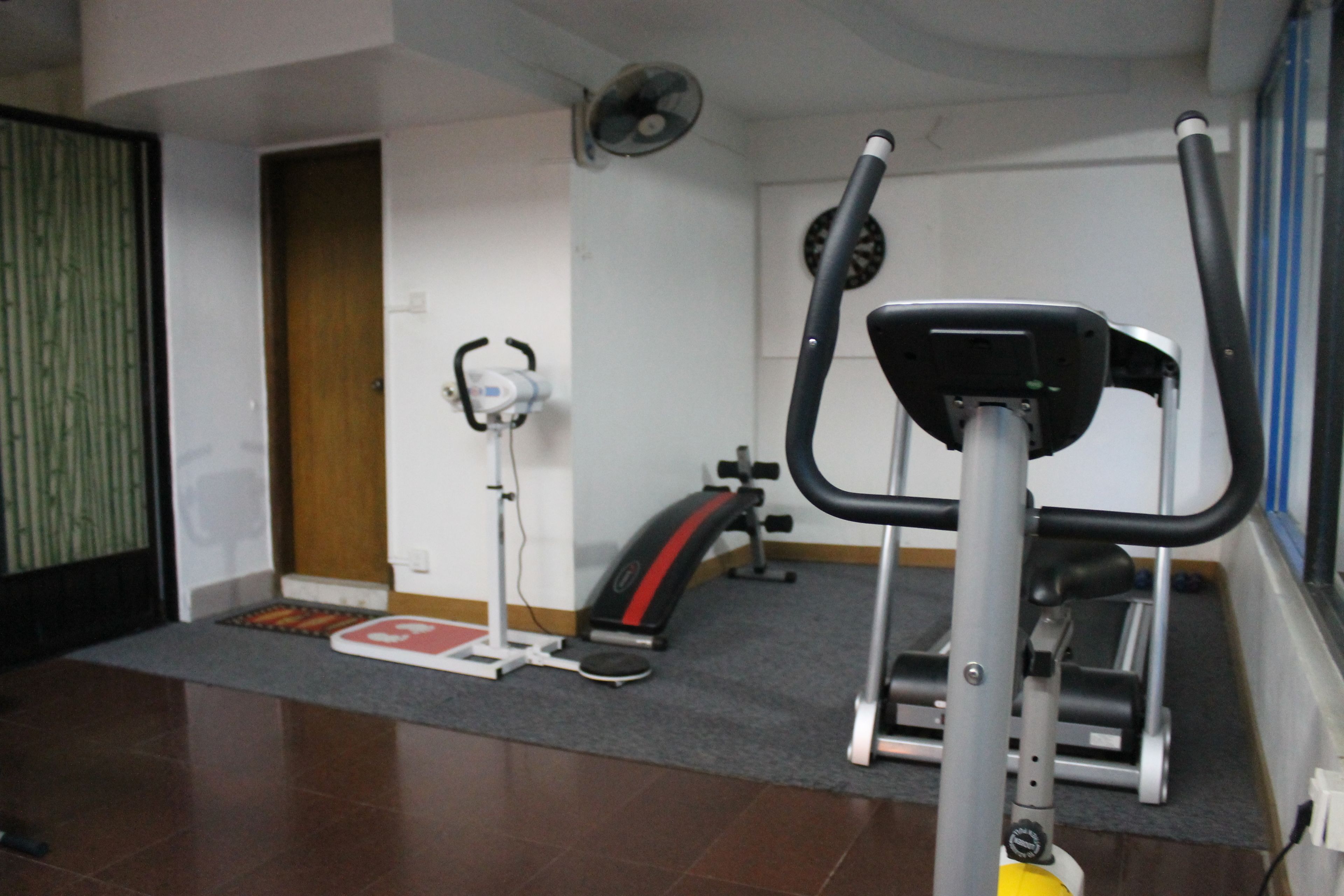 A gym with exercise equipment, a fan, and a door.