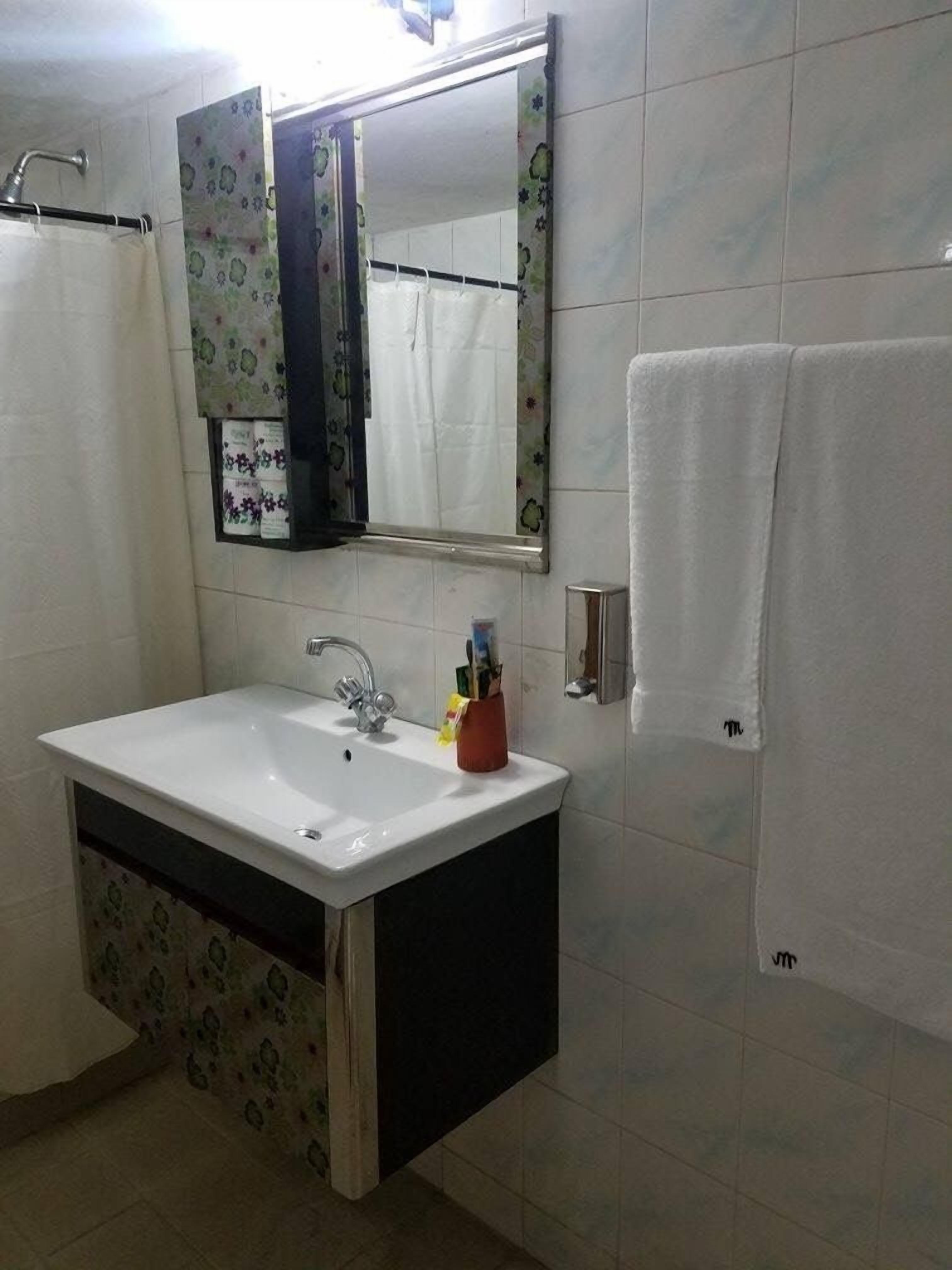 Une salle de bain avec un lavabo blanc, un miroir et une serviette accrochée au mur.