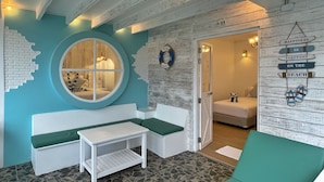 Ein Zimmer mit einem Rundfenster, einer weißen Bank, einem kleinen Tisch und einer Tür zu einem anderen Raum.