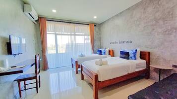 Habitación de hotel con dos camas, un escritorio y un televisor.