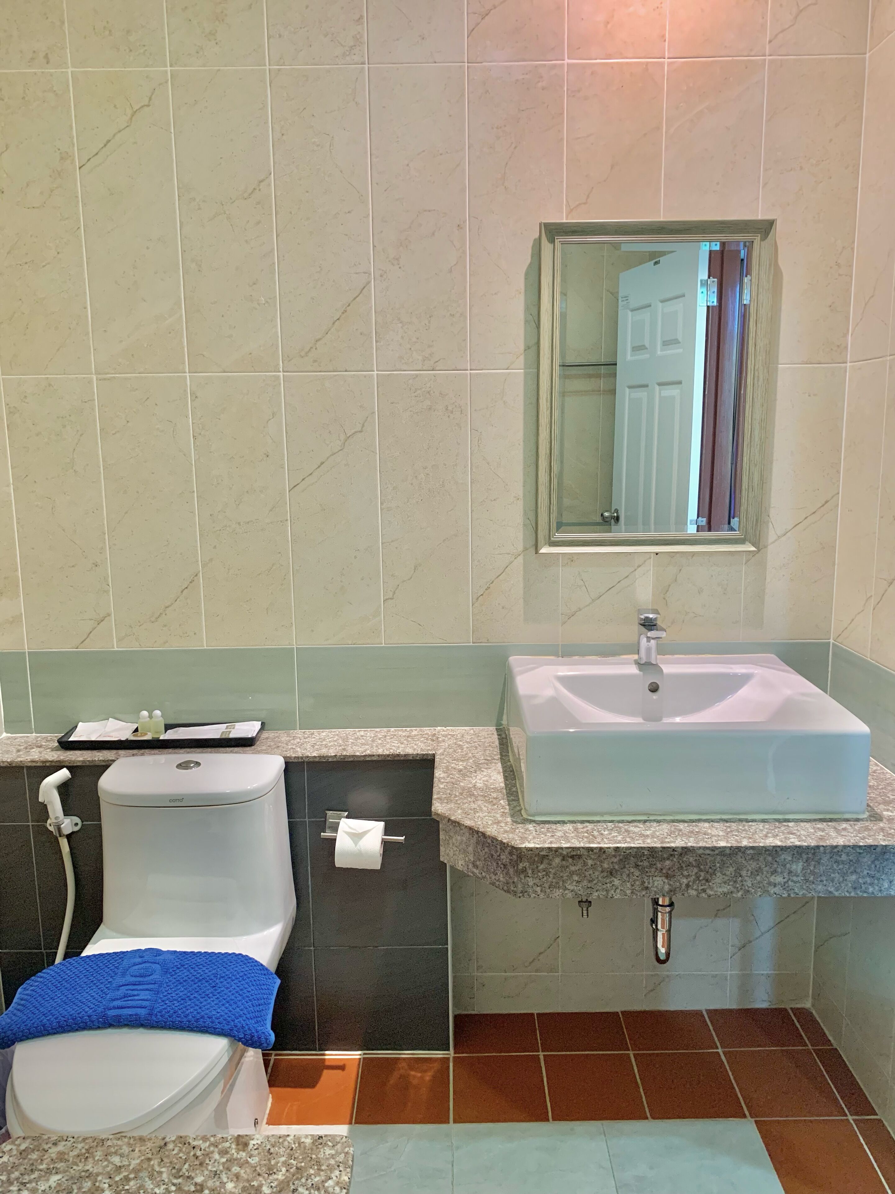 Une salle de bain équipée de toilettes, d’un lavabo, d’un miroir et d’un porte-serviettes.