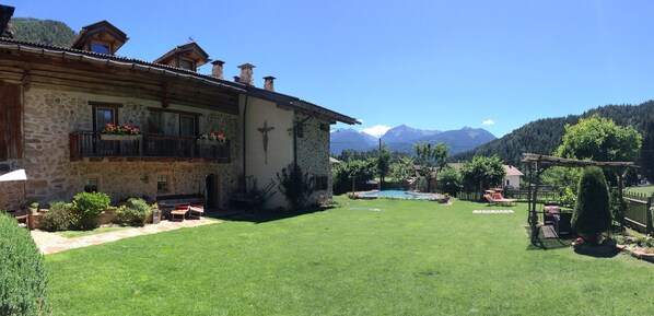 A stone building with a balcony, a pool, and a mountain backdrop. - Maso Franceschella (Ville di Fiemme)