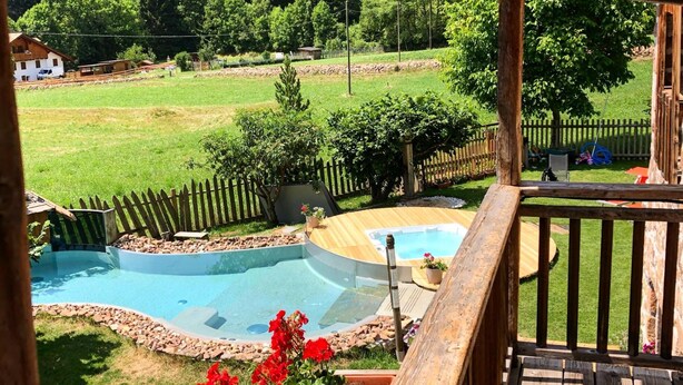 A wooden deck with a pool and a view of a green landscape. - Maso Franceschella (Ville di Fiemme)