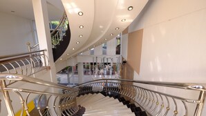 Un interior moderno con una escalera curva, barandillas de metal e iluminación empotrada.