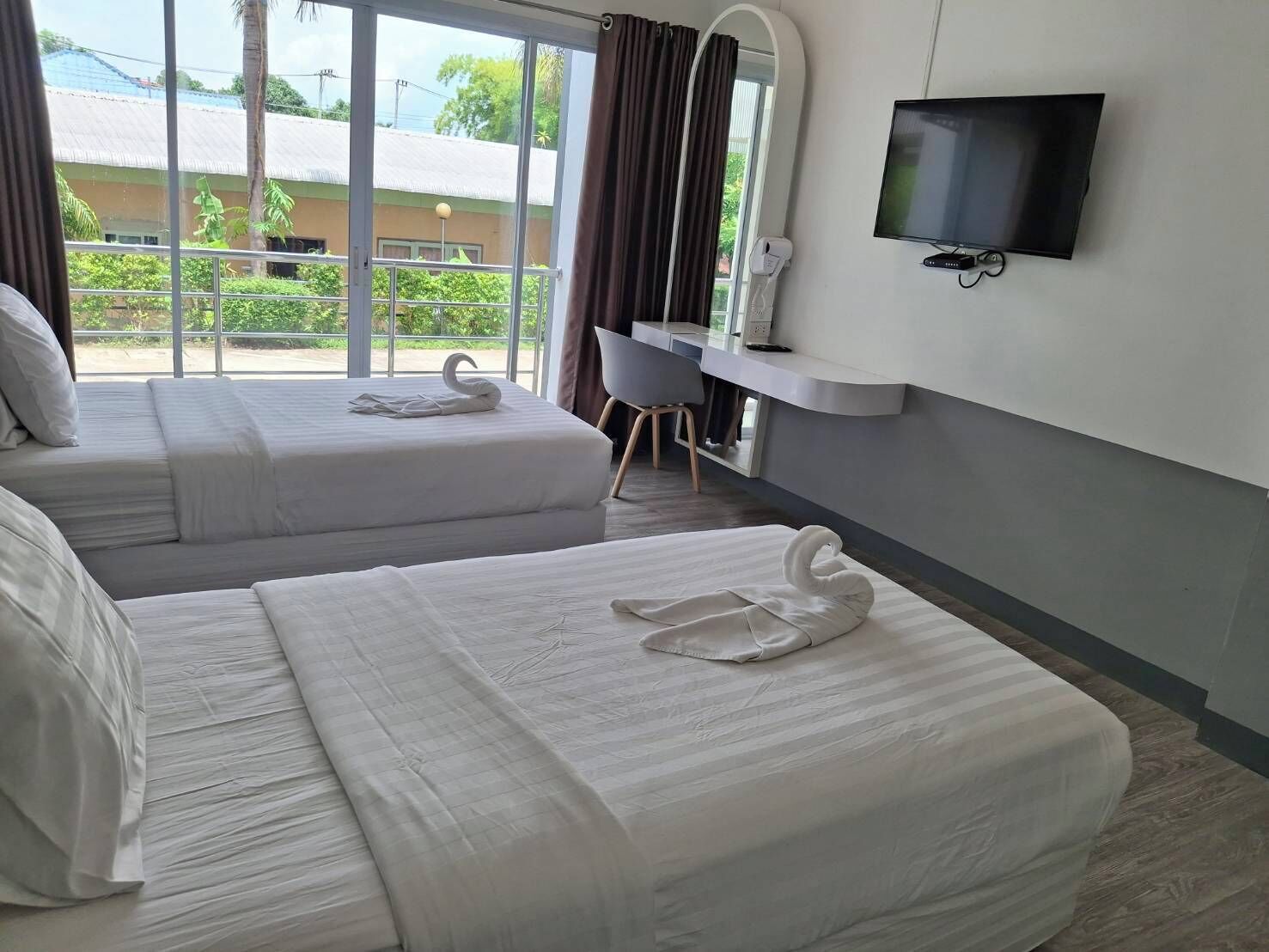 A hotel room with two beds, a TV, and a desk with a chair.