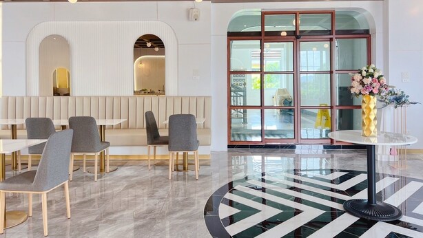 Un interior moderno con una zona de estar, una entrada con puerta de vidrio y un jarrón decorativo.