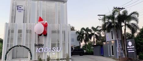 Un hotel con fachada de vidrio moderna, una gran decoración inflable de Papá Noel y un cartel con el nombre del hotel.