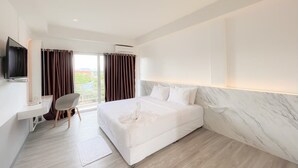 Una habitación de hotel moderna con una cama grande, un escritorio, una silla y un televisor.