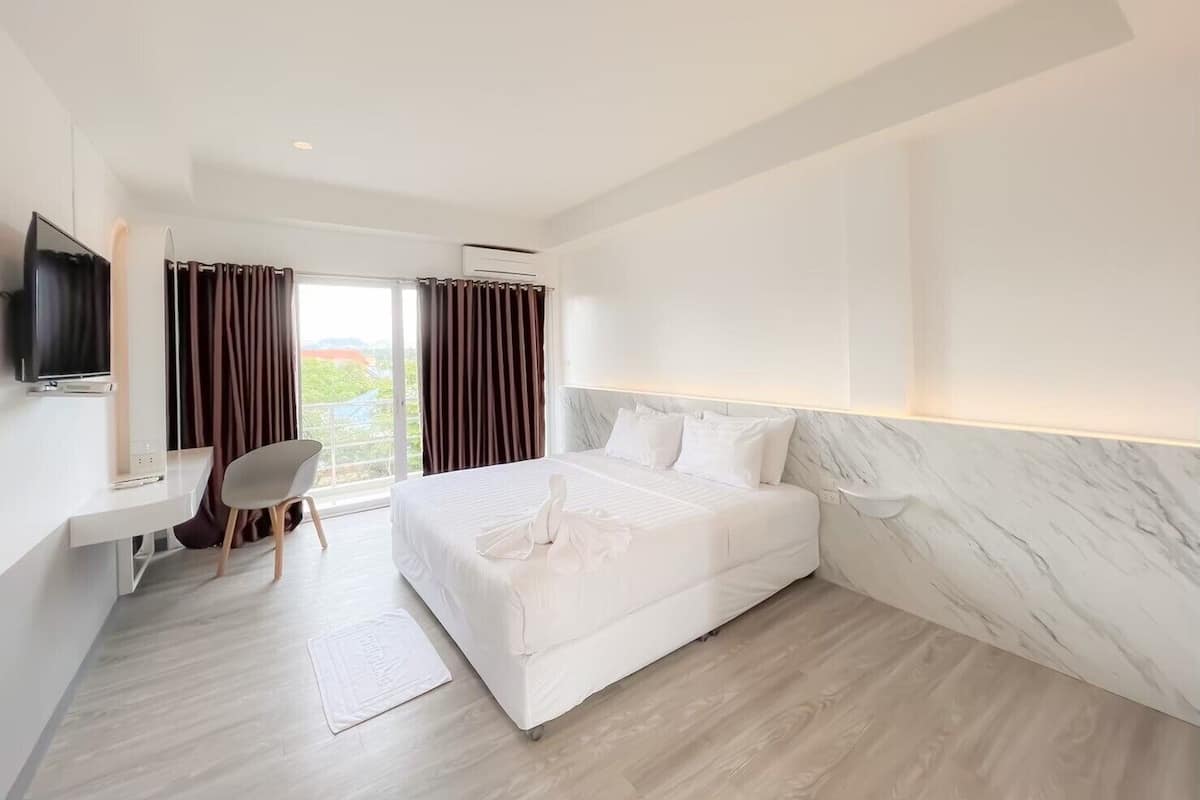 Une chambre d’hôtel moderne équipée d’un grand lit, d’un bureau, d’une chaise et d’un téléviseur.