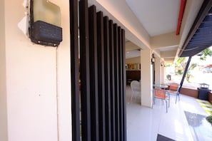 A modern indoor space with a tiled floor, a black vertical partition, and a seating area with chairs and a table.