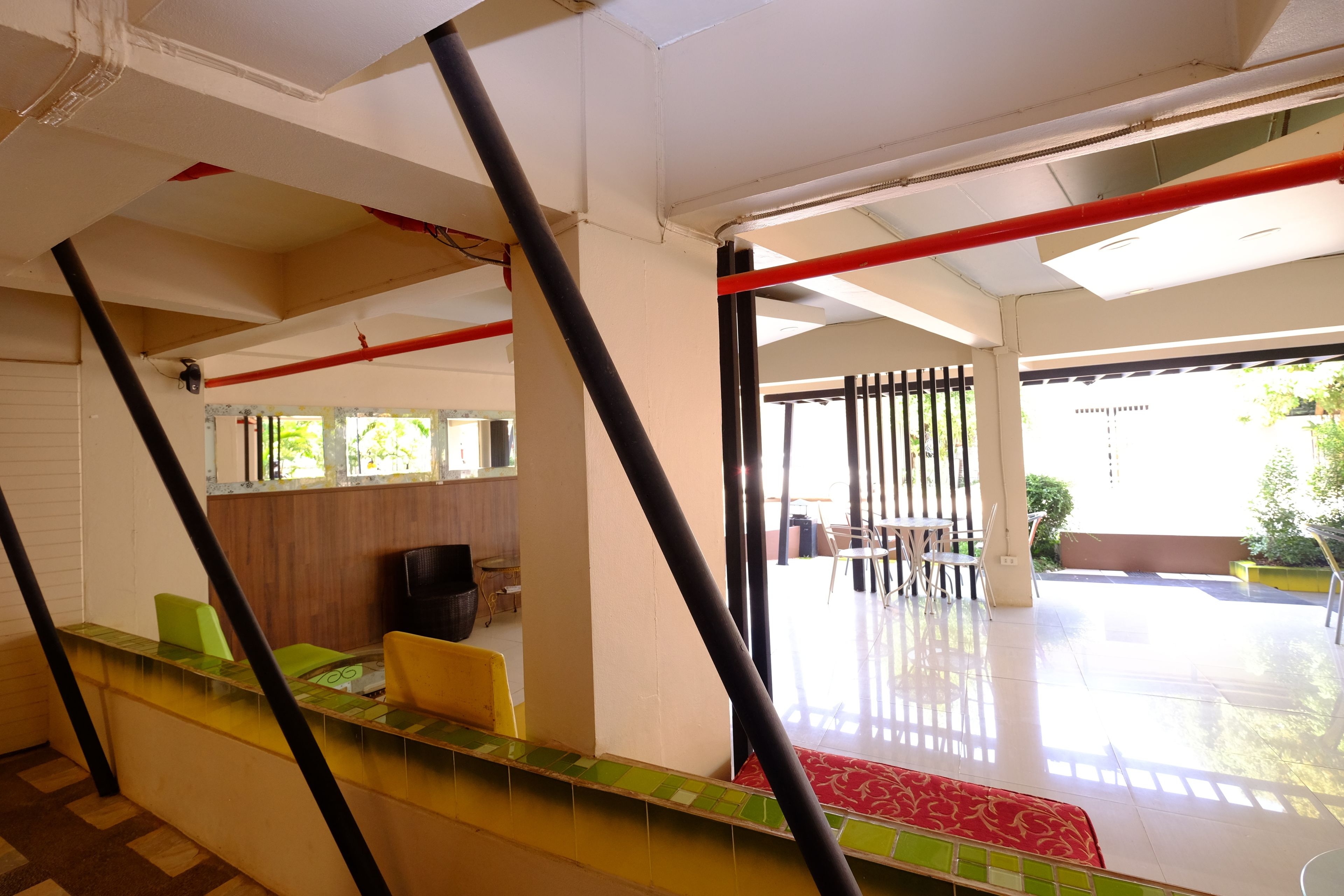 A hotel lobby with a staircase, a reception desk, and a seating area with tables and chairs.