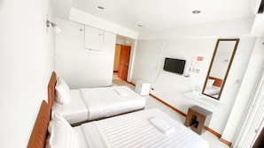 Een hotelkamer met twee bedden, een televisie, een spiegel en een klein bureau met een stoel.