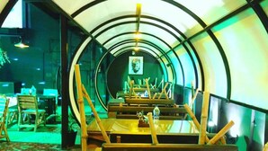 Een ronde kamer met een centrale tafel en bankjes, omgeven door een gebogen muur met een klein raam.