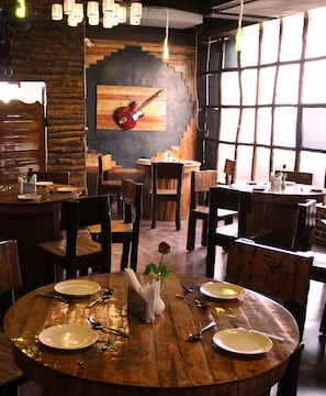 Ein Restaurant mit Holztischen und -stühlen, einer Gitarre an der Wand und einer Rose auf dem Tisch.