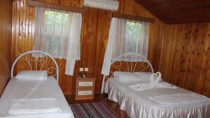Ein Holzhütten-Zimmer mit zwei Betten, einem Nachttisch und einer Klimaanlage.