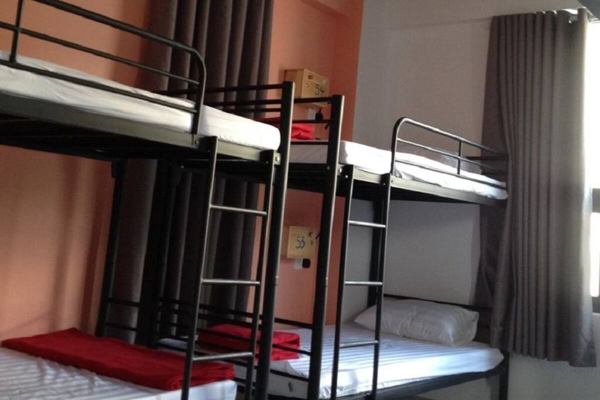 Een slaapkamer met stapelbed, raam en gordijnen.