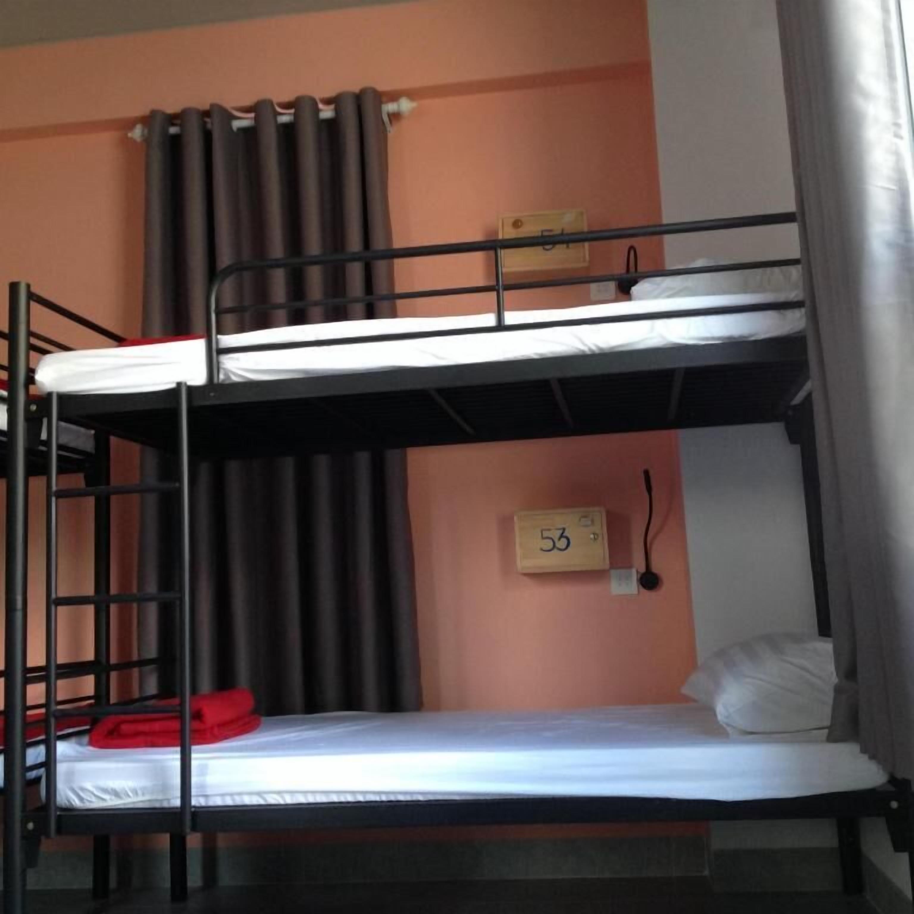 Une chambre avec des lits superposés, un panneau indiquant le numéro « 53 » étant fixé au mur.