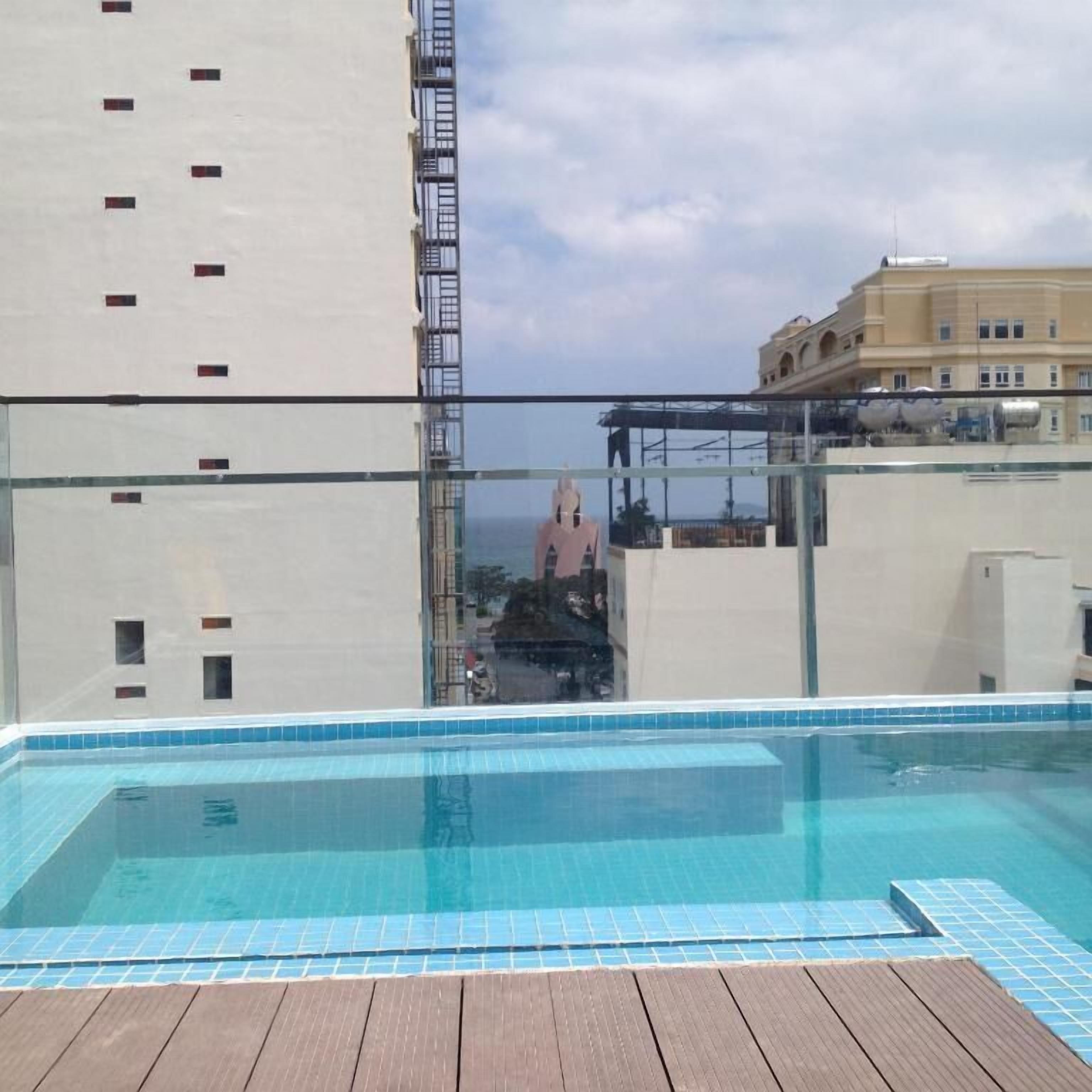 A rooftop pool with a clear view of the cityscape, including a tall building and a bridge.