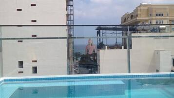 A rooftop pool with a clear view of the cityscape, including a tall building and a bridge.