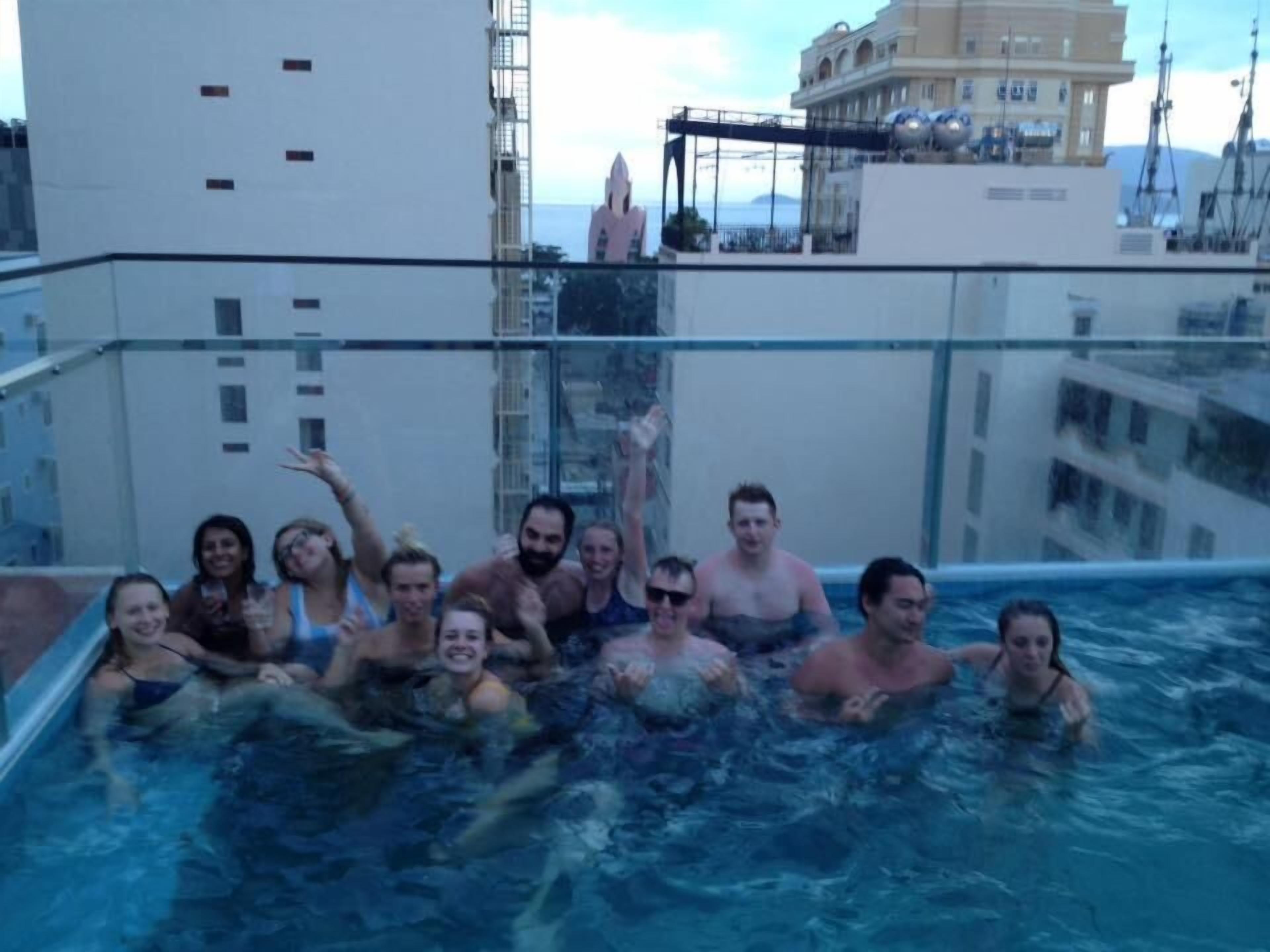 A group of people in a rooftop pool with a cityscape in the background.