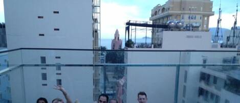 A group of people in a rooftop pool with a cityscape in the background.