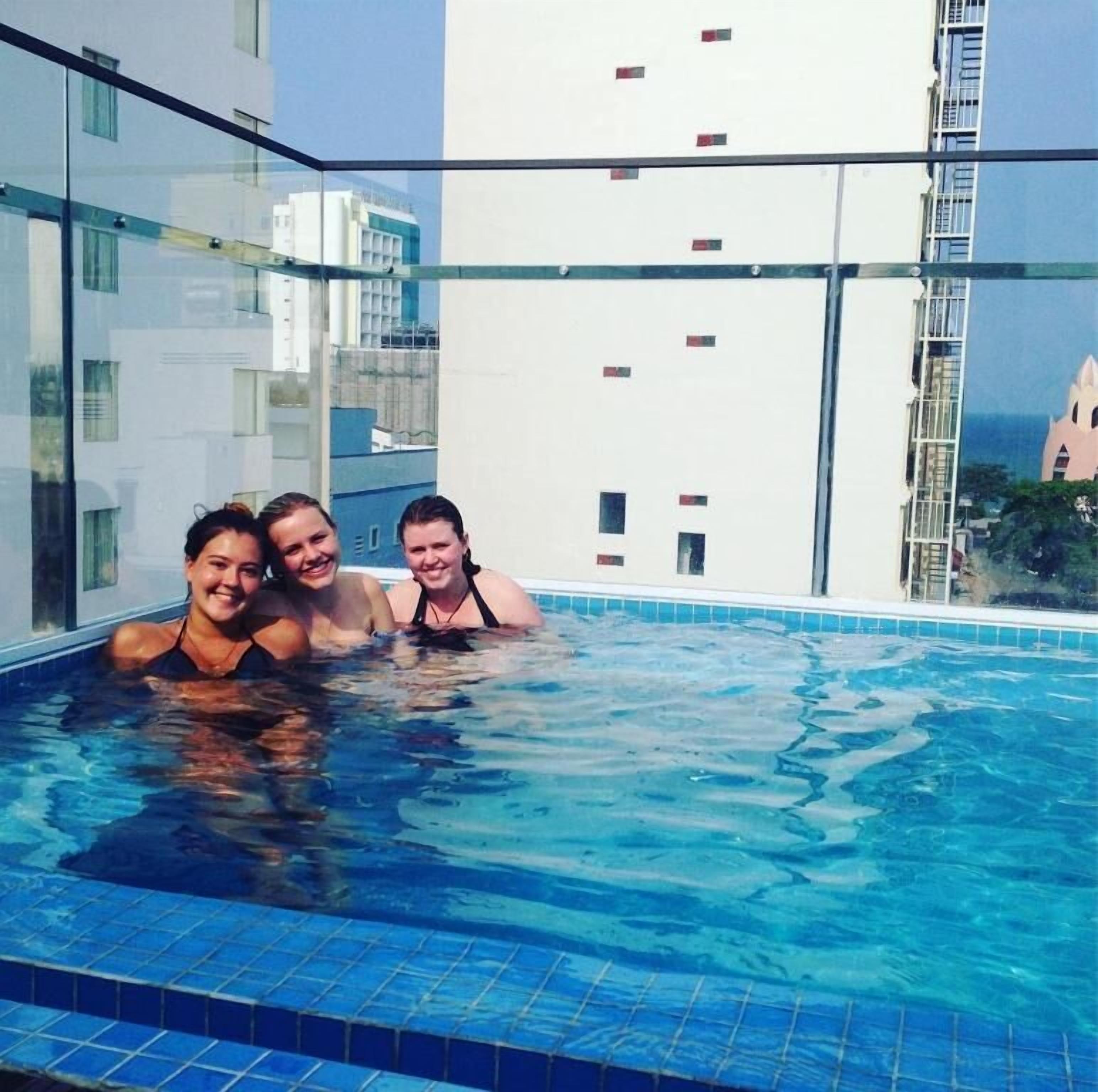 A rooftop pool with three people.