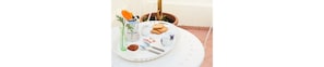 A round table with a white plate, a green glass, a white pitcher, a small bowl, and a few items on a tray. - B&B Bari Old Town (Bari)