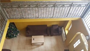 Blick von oben auf ein Wohnzimmer mit einem braunen Sofagarnitur, einem kleinen Holztisch und einem Weihnachtsbaum.