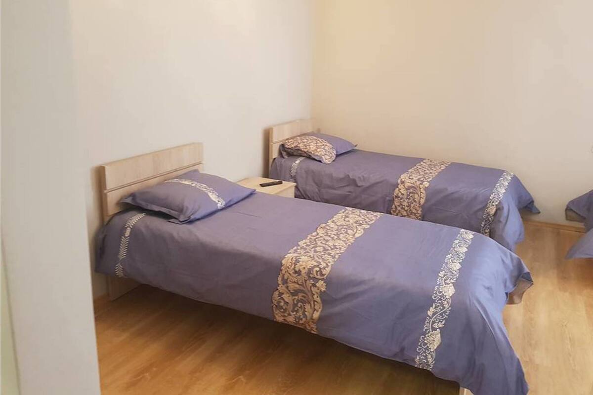 Une chambre avec deux lits simples, chacun doté d’une tête de lit en bois et d’un oreiller assorti.
