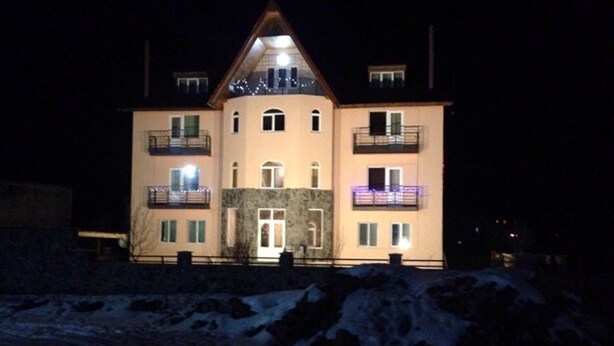 Ein mehrstöckiges Gebäude mit einem zentralen Eingang, Balkonen und einem mit Schnee bedeckten Untergrund.