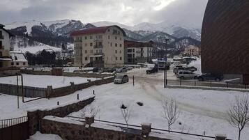 Um estacionamento coberto de neve, com vários carros e um edifício ao fundo.