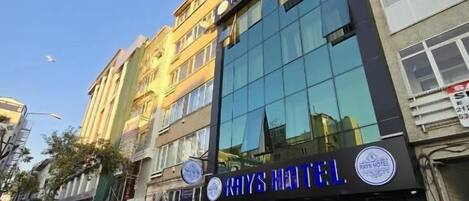 A hotel with a modern facade, large windows, and a prominent sign for "Rays Hotel".
