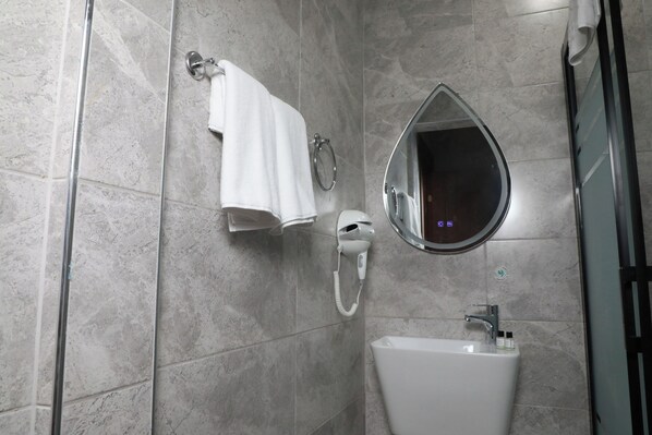 Un baño con lavamanos blanco, secador de pelo, toallero y espejo.