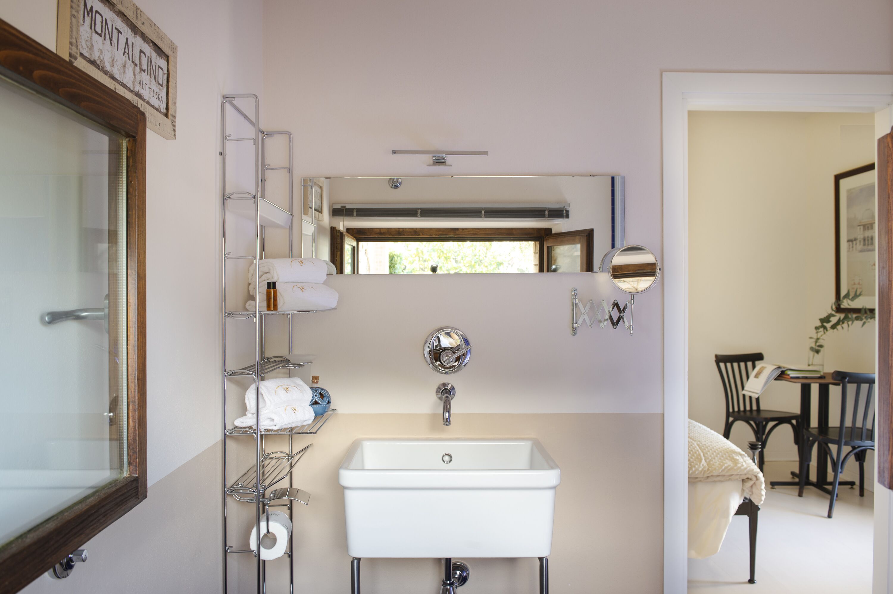 A bathroom with a white sink, a mirror, a towel rack, and a shower area.
