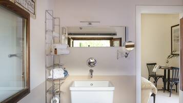 A bathroom with a white sink, a mirror, a towel rack, and a shower area.