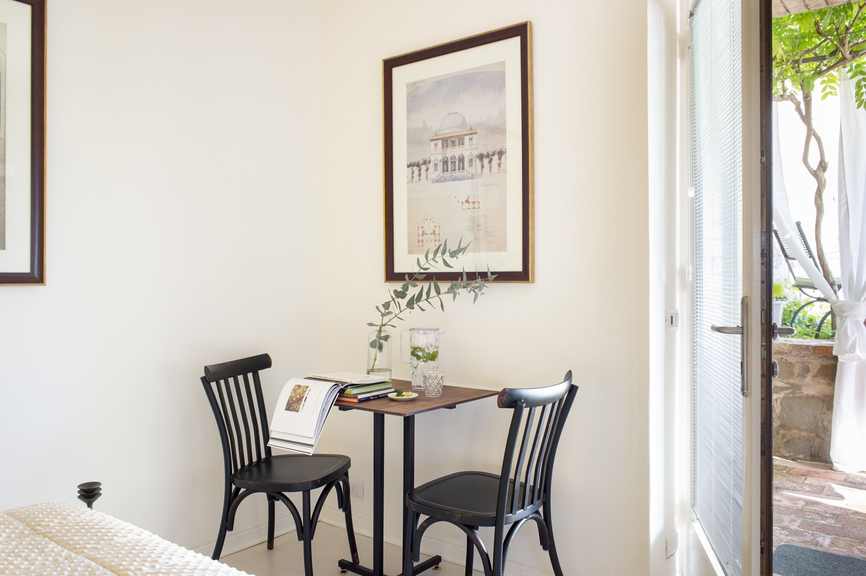 A dining area with two chairs, a table, and a framed picture on the wall.