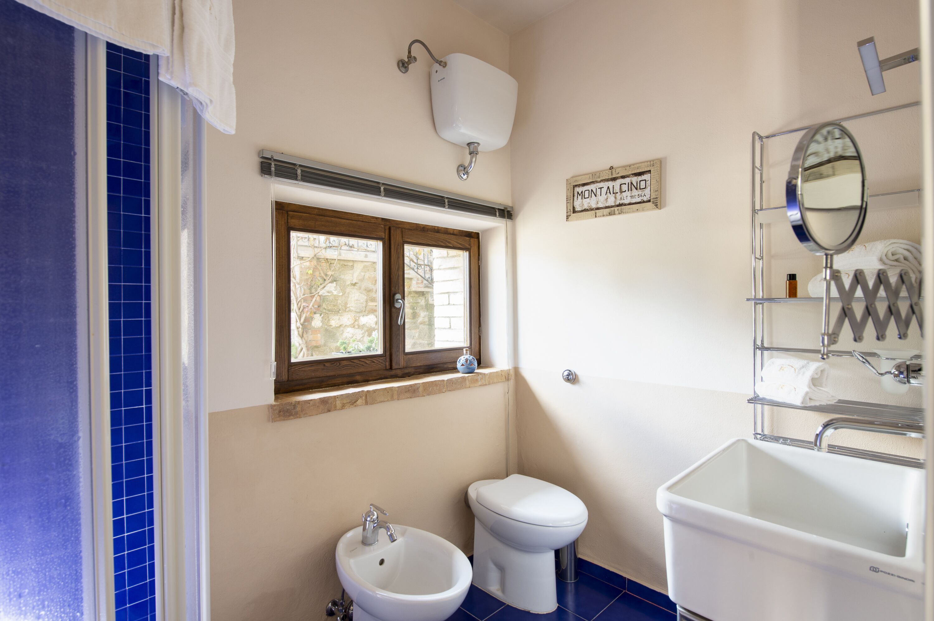 Un baño con bidé, inodoro, lavabo y ventana con vistas al exterior.