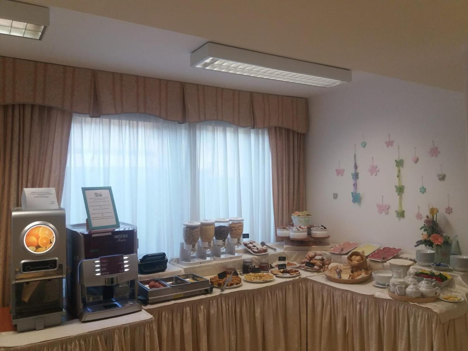 Un buffet proposant divers plats, une machine à café et une fenêtre avec des rideaux.