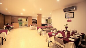A spacious dining area with multiple tables set for meals, a reception desk, and an air conditioning unit on the wall. - Bashati Bay Resort (Cox's Bazar)
