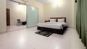 A bedroom with a bed, a ceiling fan, a nightstand, a green curtain, and a sliding door leading to another room. - Bashati Bay Resort (Cox's Bazar)