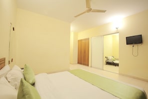 A bedroom with a bed, pillows, a ceiling fan, a TV, and a wardrobe. - Bashati Bay Resort (Cox's Bazar)