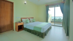 A bedroom with a bed, a nightstand, a ceiling fan, and a view through a large window. - Bashati Bay Resort (Cox's Bazar)