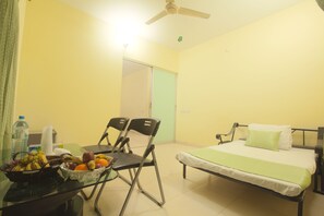 A room with a bed, a table with chairs, and a fruit bowl.