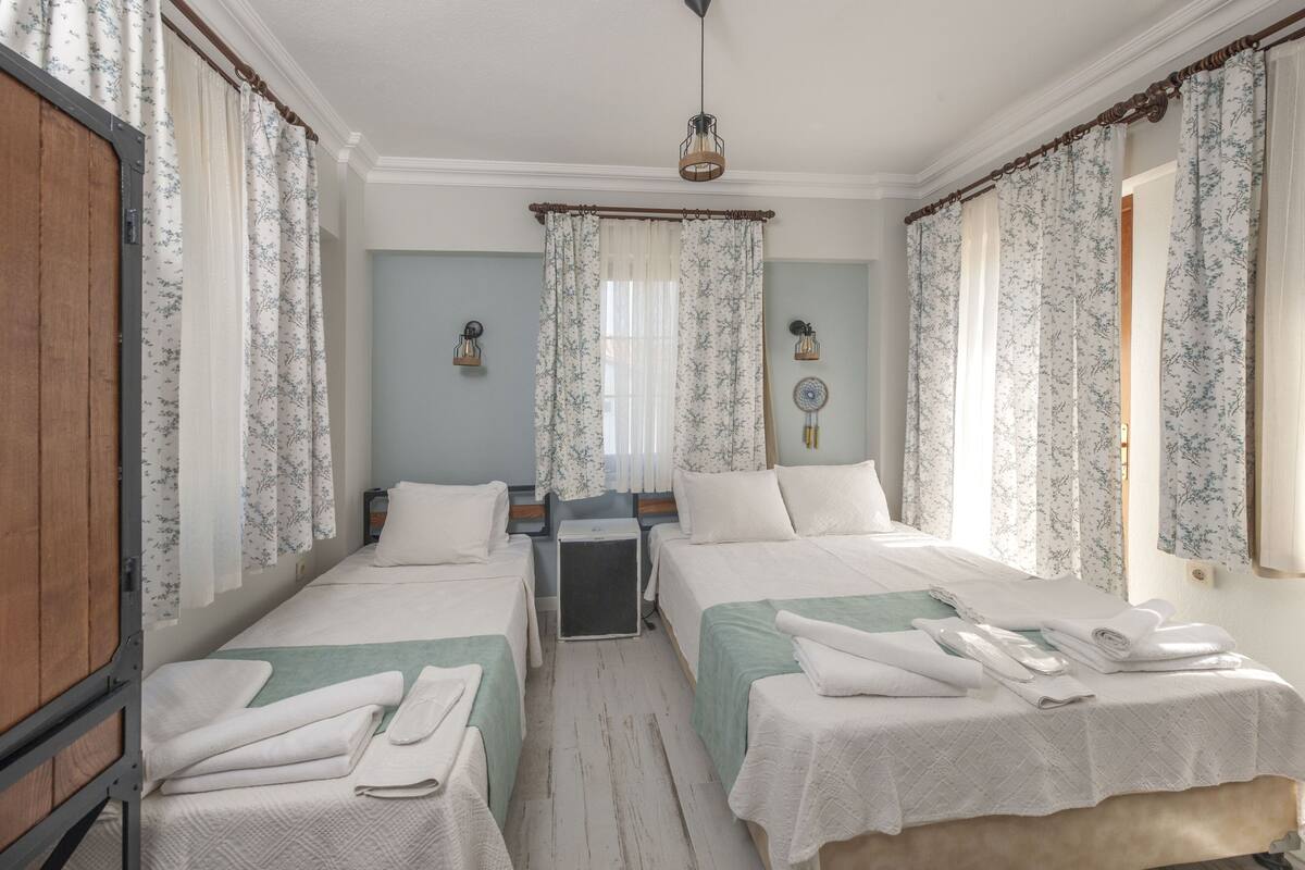 Une chambre avec deux lits, une armoire en bois et une petite table.