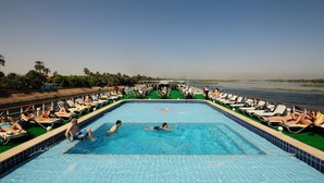 Ein Pool mit Schwimmern und Liegebädern, umgeben von Stühlen und Blick auf das Wasser.