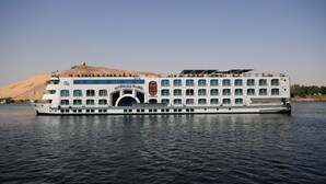 Ein großes Flusskreuzfahrtschiff mit mehreren Decks und einem markanten Bogenportal.