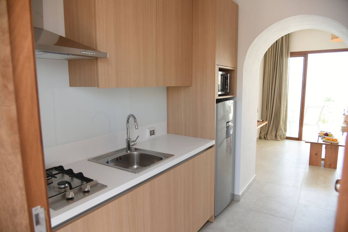 Una cocina moderna con armarios de madera, electrodomésticos de acero inoxidable y encimera blanca.