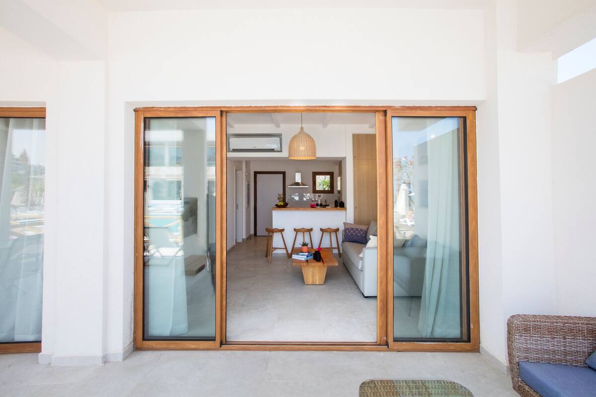 Un espacio habitable moderno con un divisor de vidrio corredizo que da a una cocina.