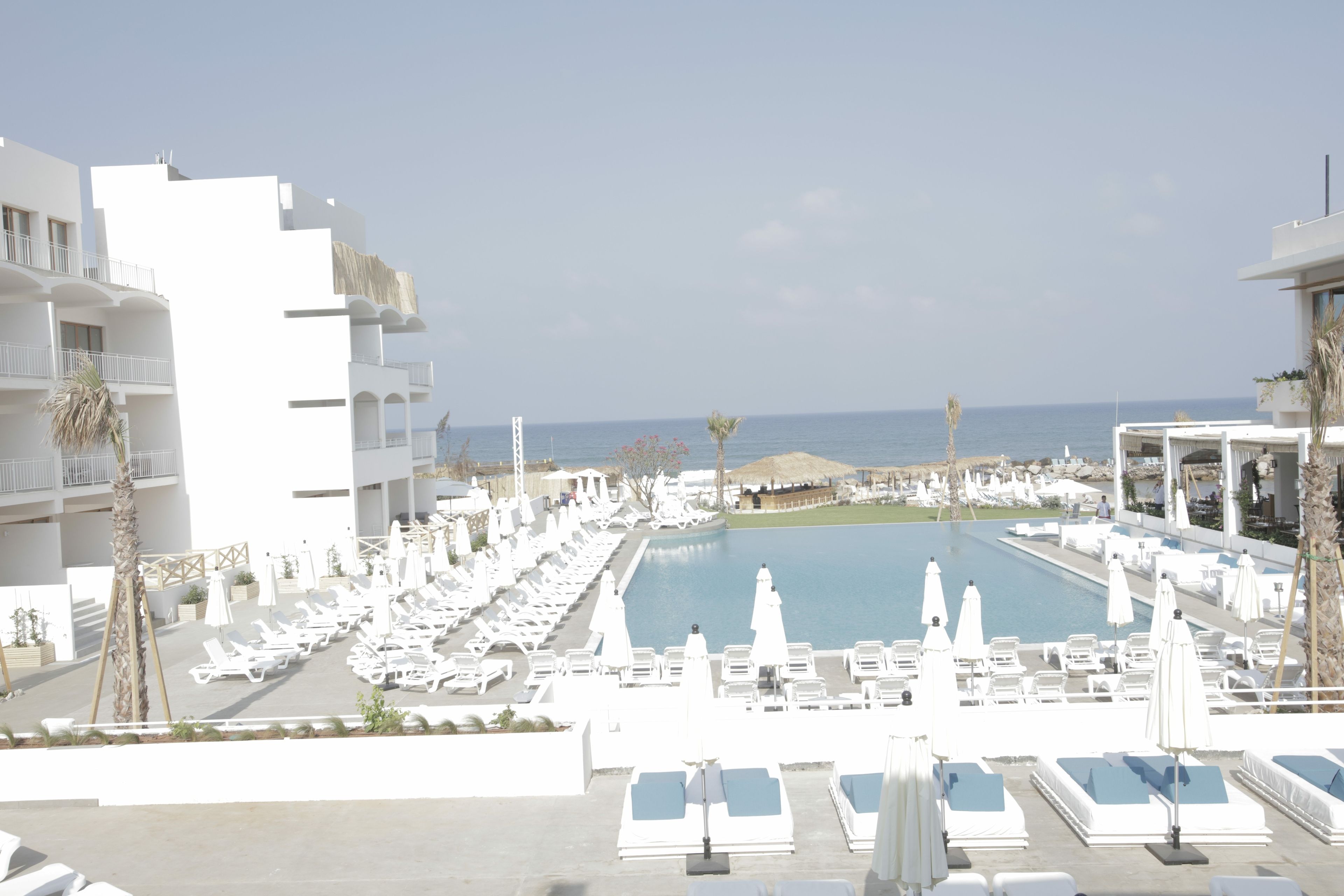 Un resort con zona de piscina, tumbonas y vista al mar.