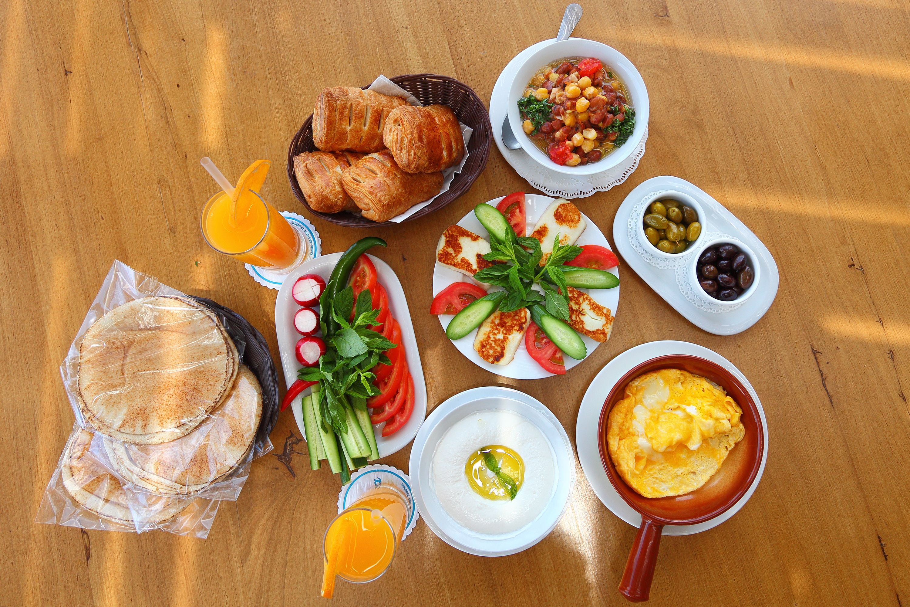 A table with various breakfast items including bread, vegetables, and a bowl of soup.